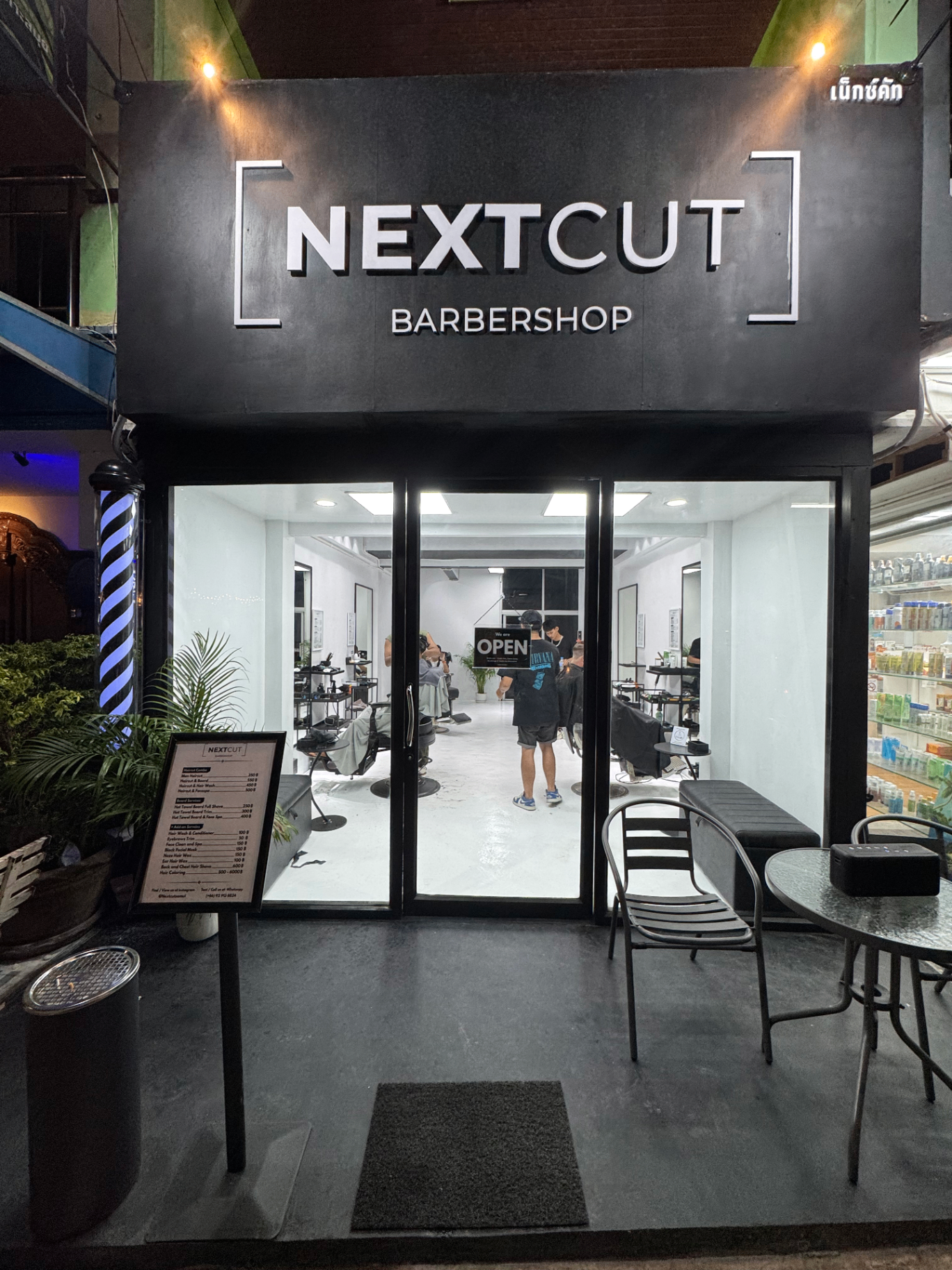 NextCut Barbershop storefront in Fisherman's Village at night